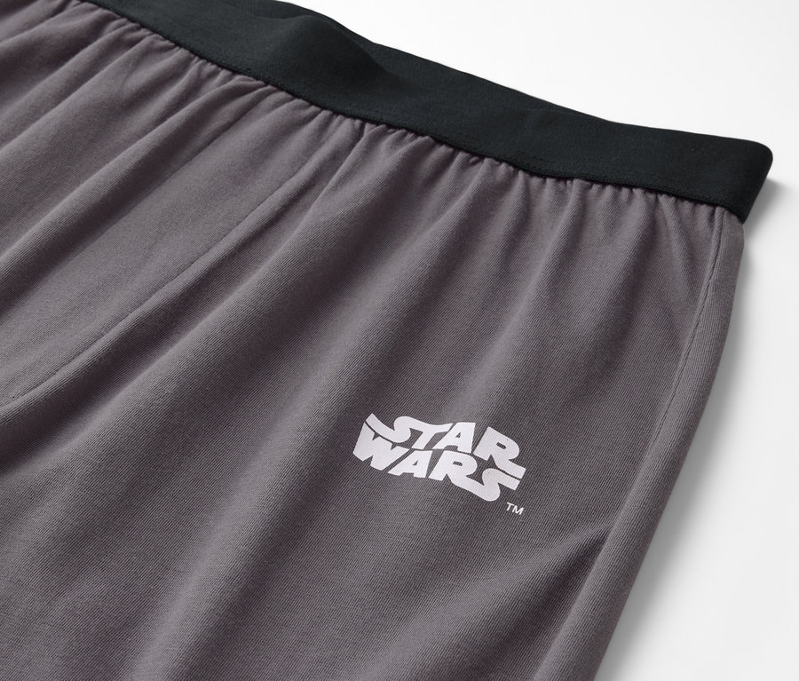 Detail šedých kalhot s černým pasem a logem Star Wars.