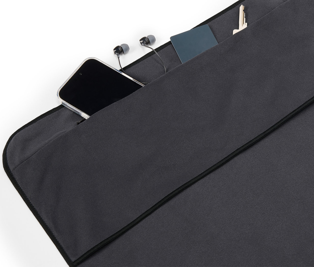 V kapse černé látky leží mobilní telefon, sluchátka, karta a klíč.