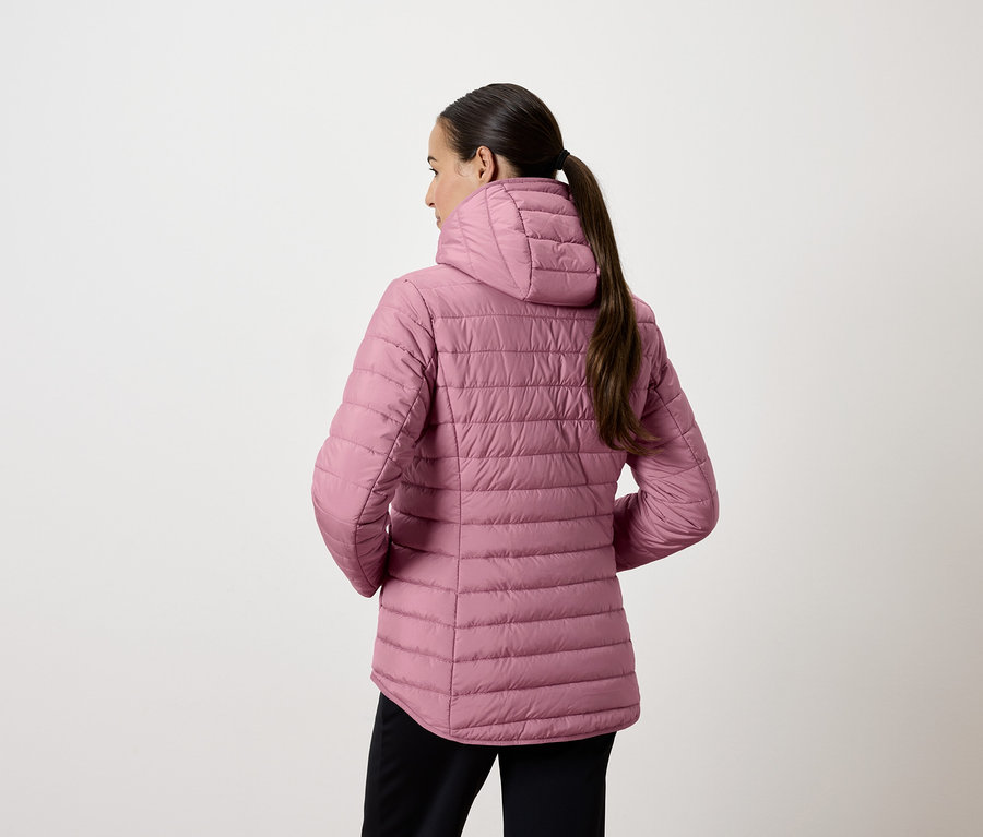 Žena v růžové prošívané bundě s kapucí, otočená zády.