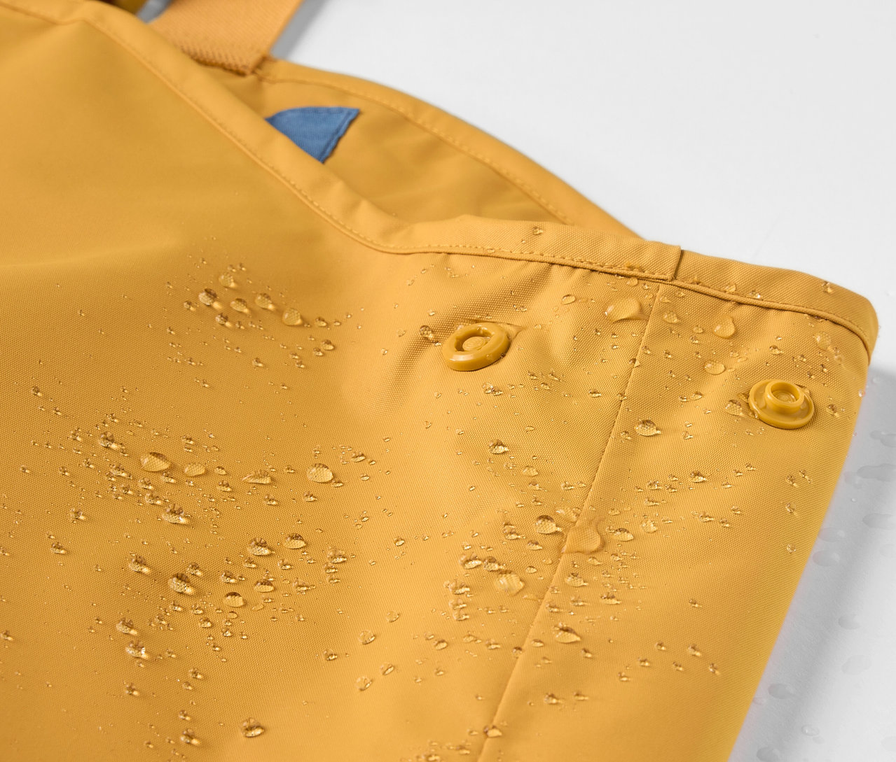 Detail dětských kalhot do deště s kapkami vody.