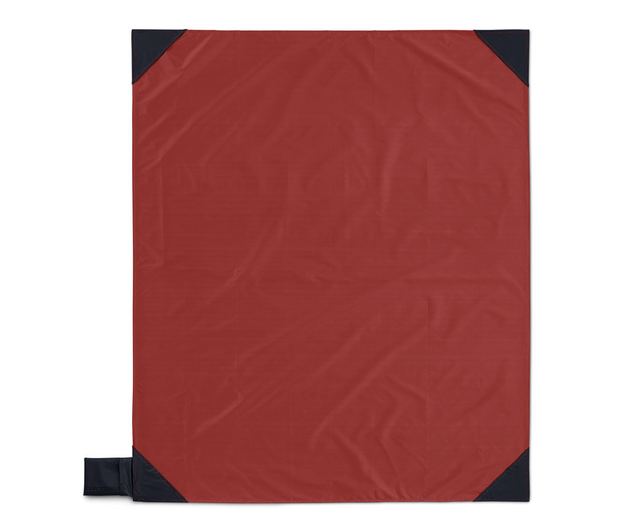 Červená mini deka na piknik s tmavě modrými rohy.