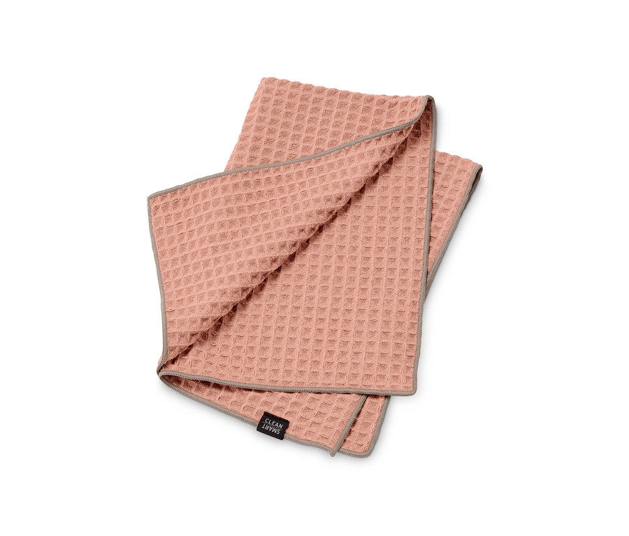 Růžová utěrka Speciální utěrka s šedým lemem leží složená na bílém pozadí.