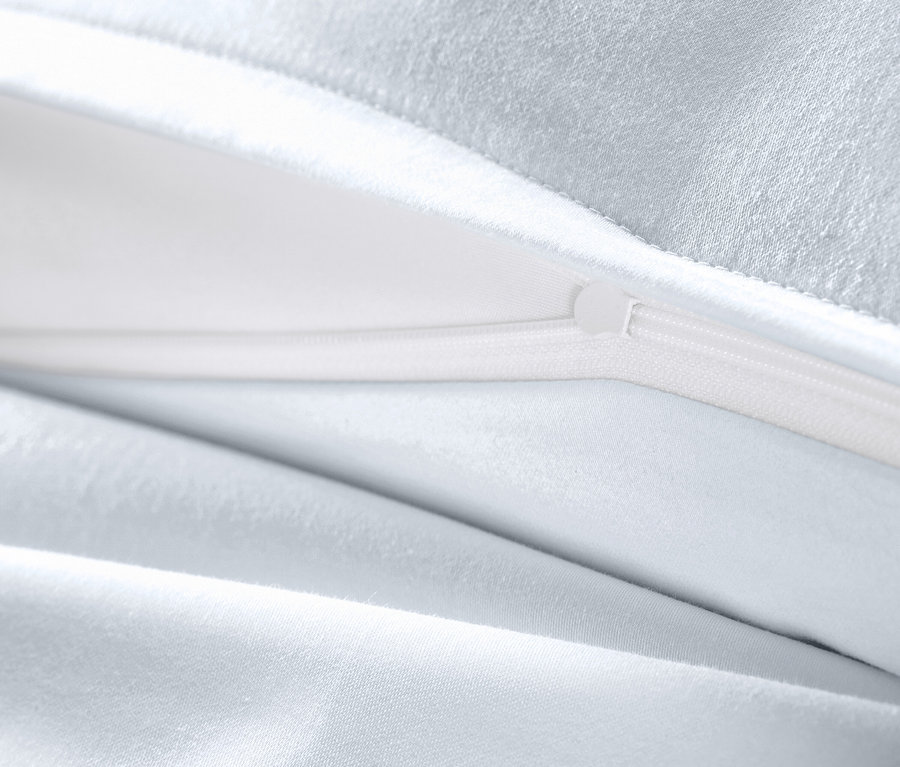 Detail bílého saténového povlečení s rozepnutým zipem.