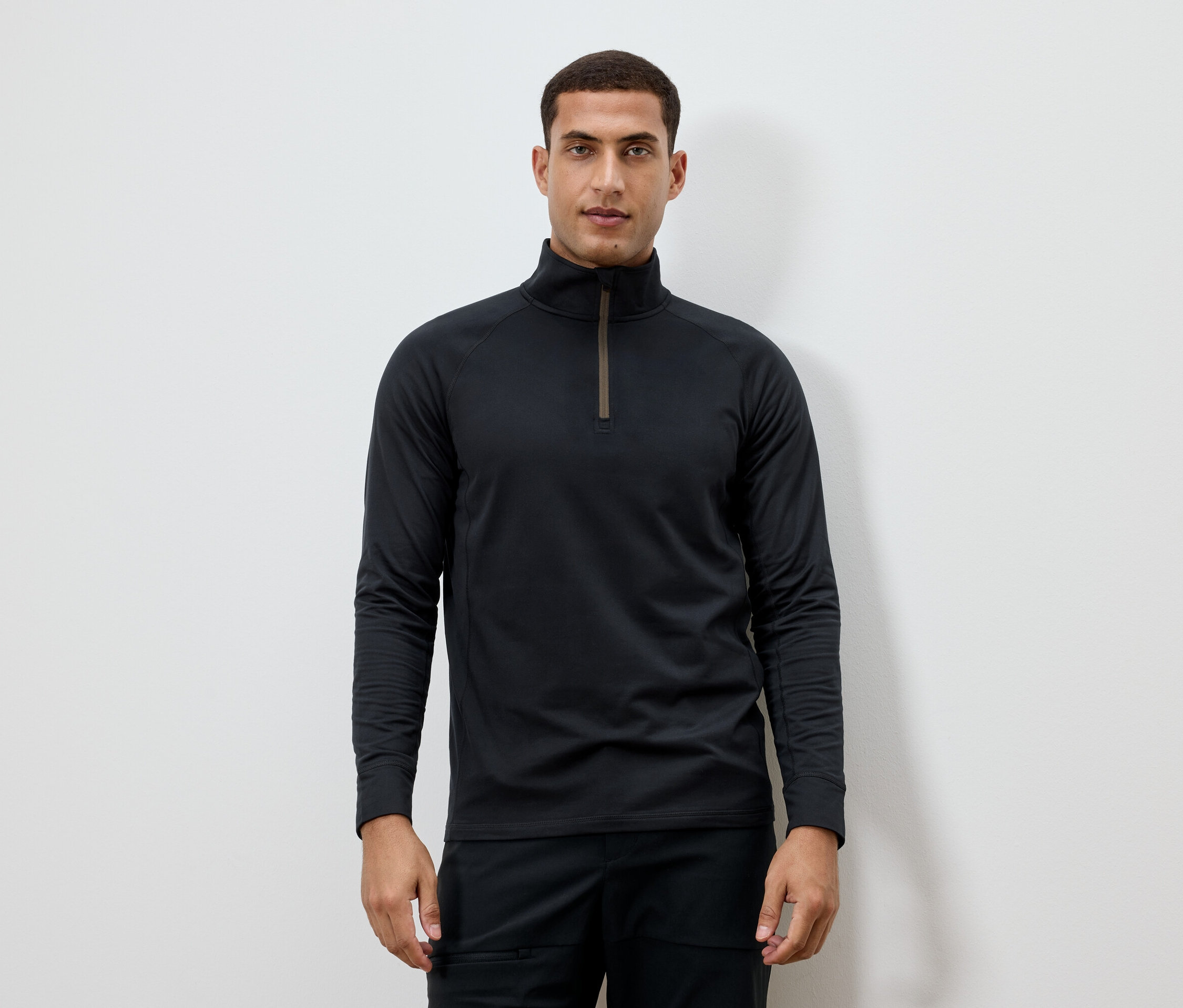 Muž má na sobě černé tričko s dlouhým rukávem a zipem u krku.