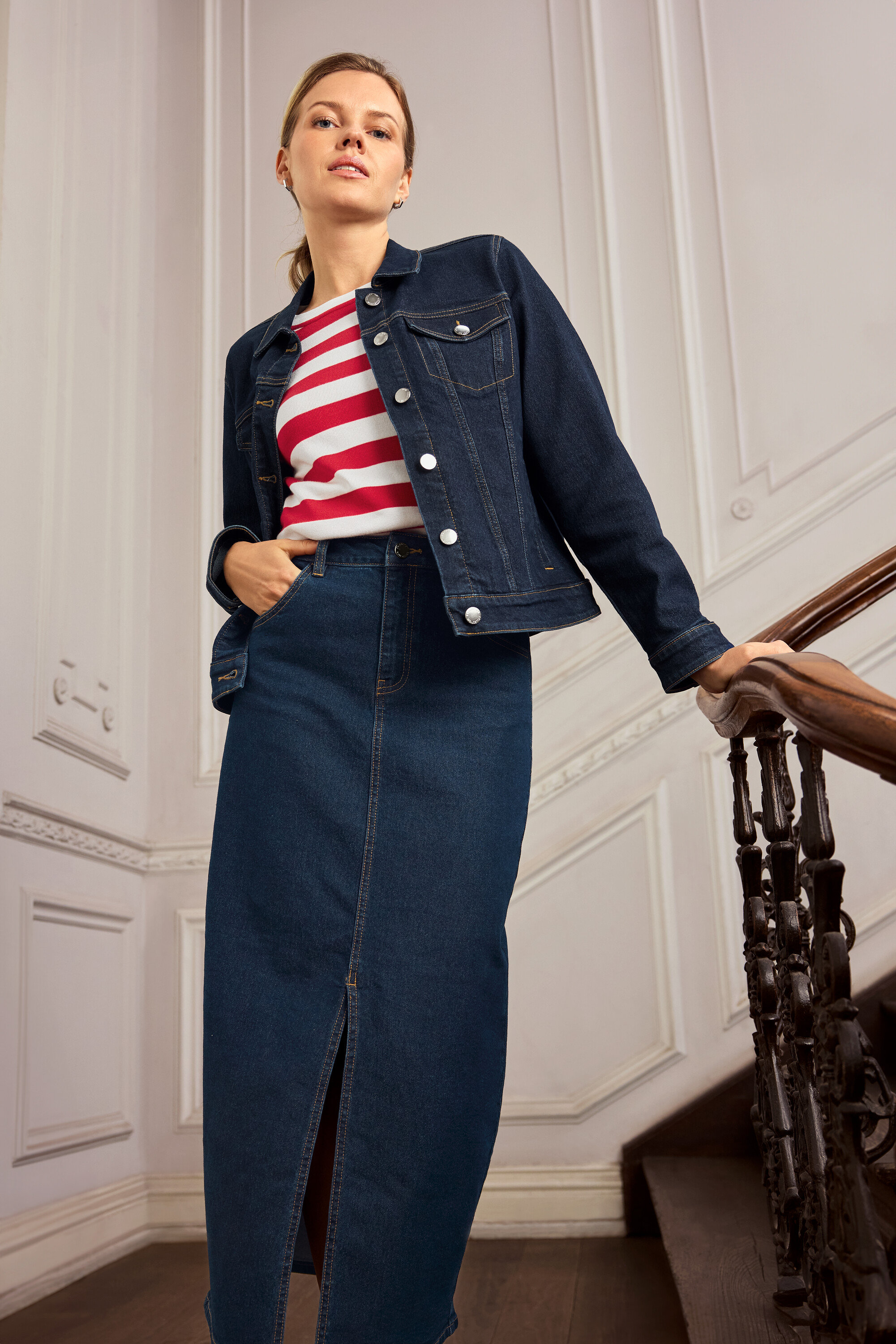 Žena v džínové bundě a sukni pózuje na schodech. Má na sobě náušnice 925 Silver Creolen Hexagon.