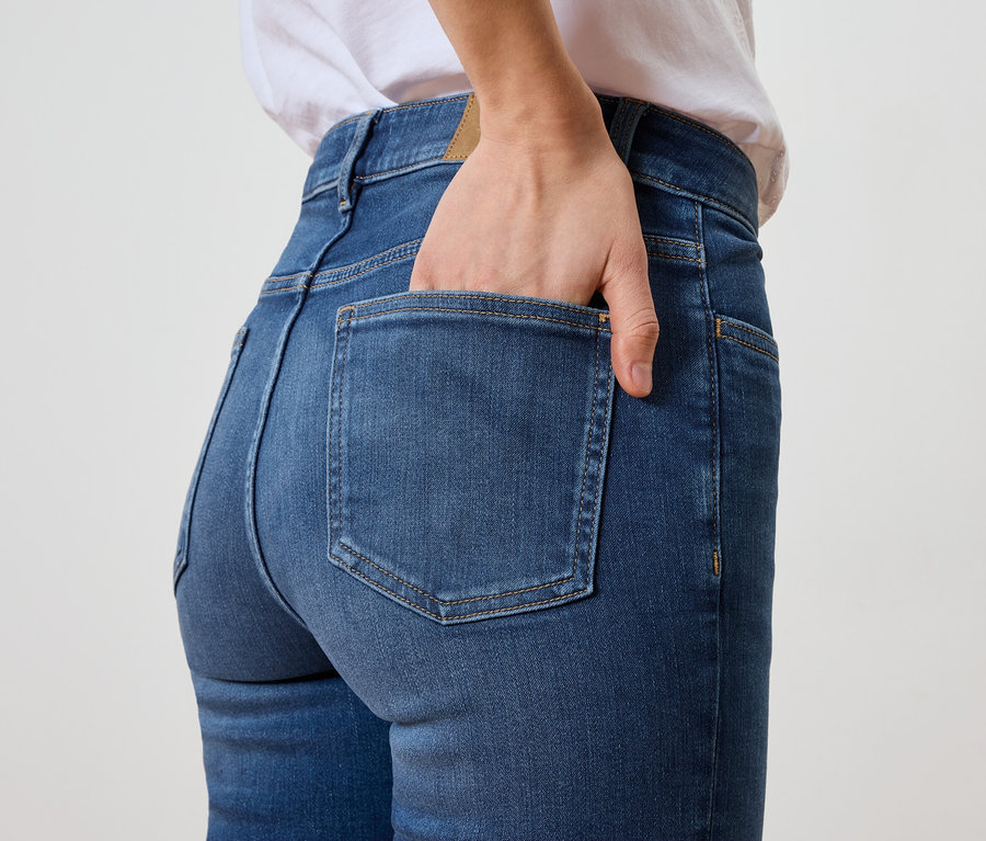 Žena má ruku v zadní kapse modrých džínů.