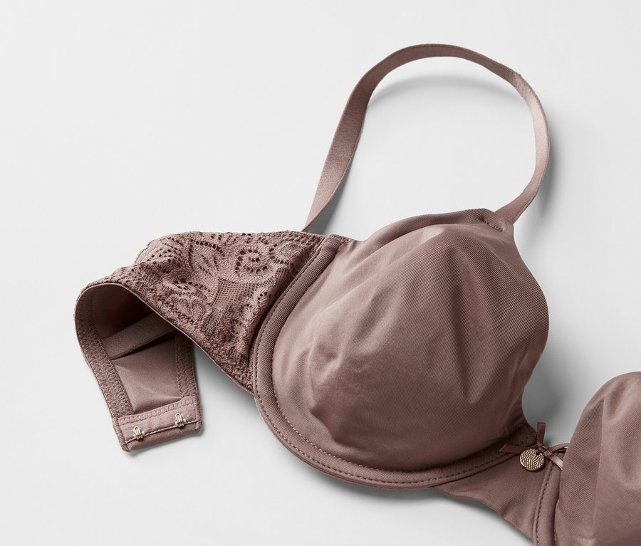 Detailní záběr na podprsenku v barvě mauve s krajkovými detaily na bílém pozadí.
