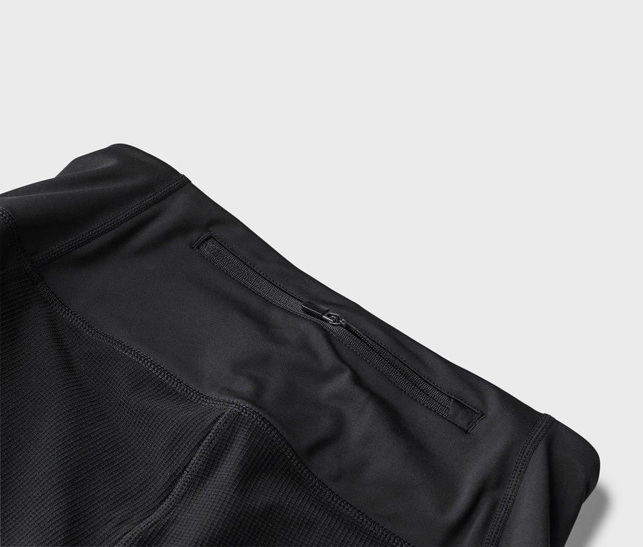 Detailní pohled na černou sportovní bundu s kapsou na zip.
