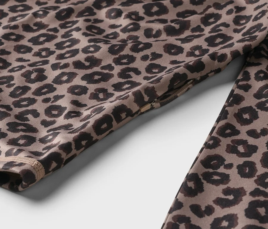 Detailní záběr sportovního oblečení s leopardím vzorem a detaily zipu.