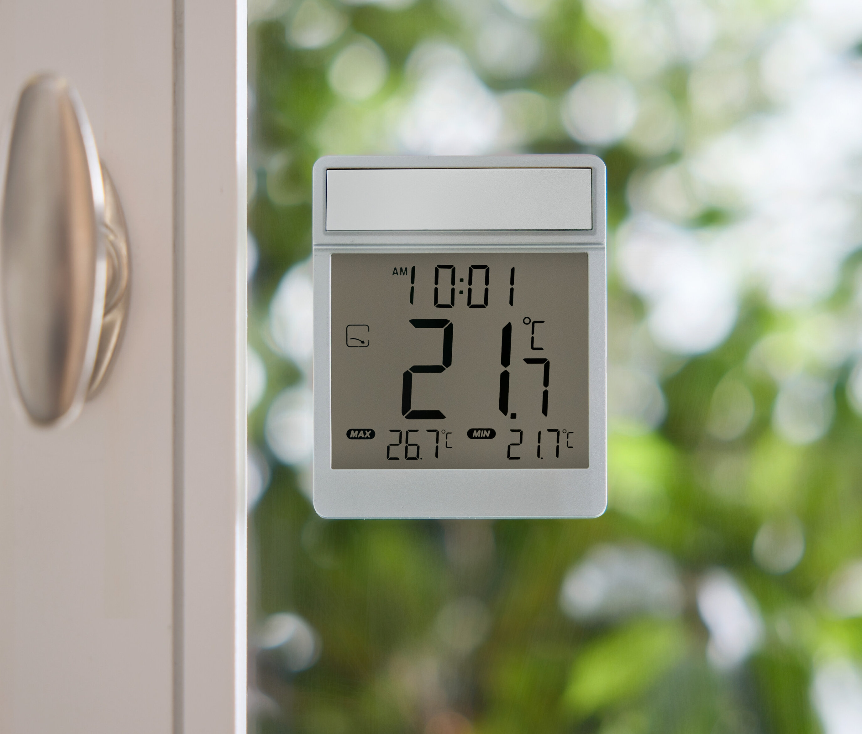 Digitální teploměr ukazuje 21,7 stupňů Celsia na okenní tabuli.