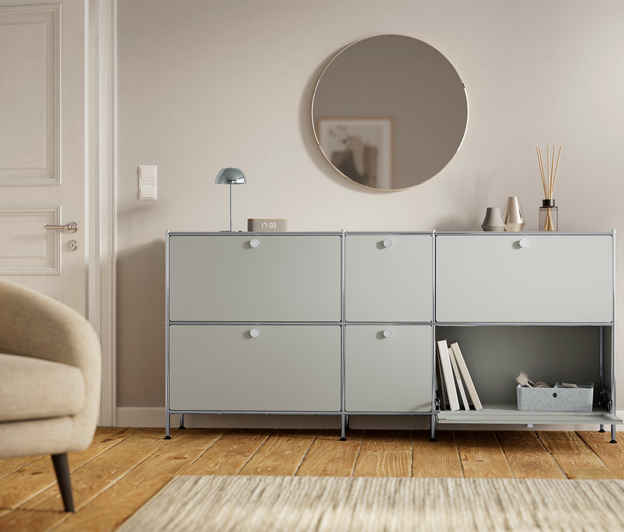 Šedá skříň se šesti přihrádkami stojí vedle dveří a křesla.