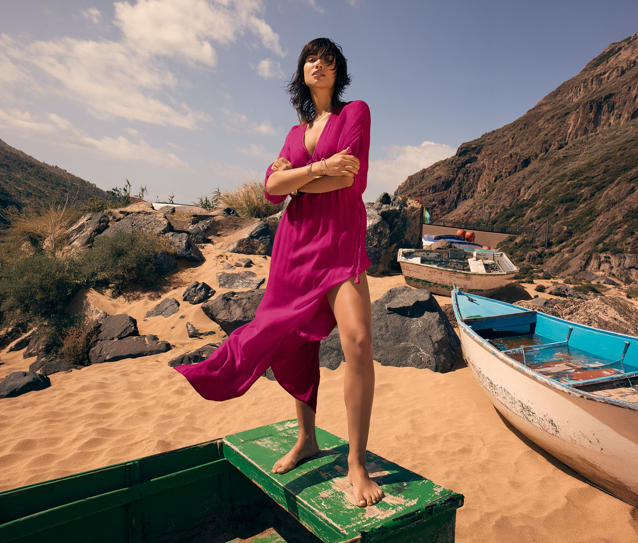 Žena stojí bosá na lodi na pláži a má na sobě maxi šaty Triumph Beach MyWear Kaftan.