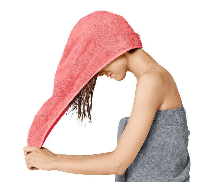 Žena si dává na mokré vlasy ručníkový turban.