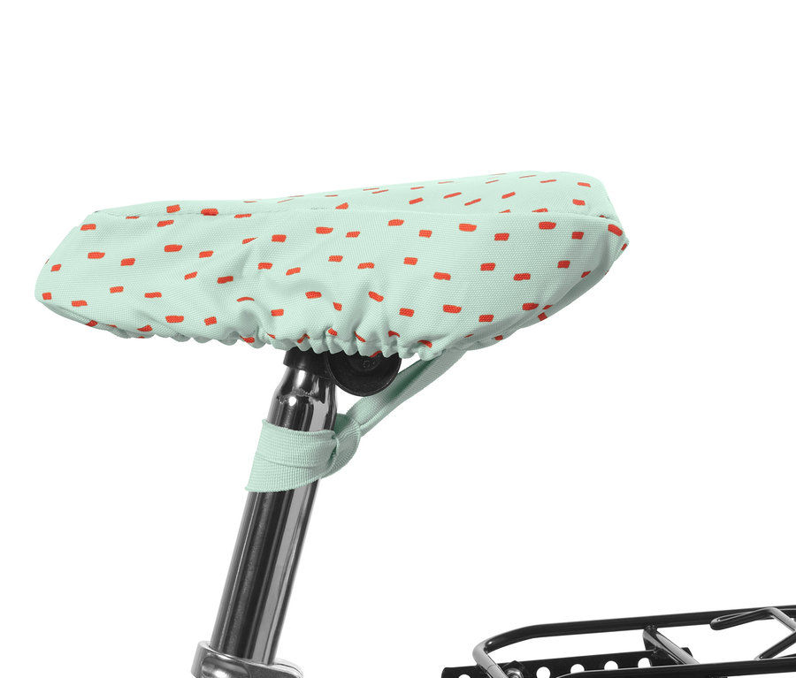 Dětský potah na cyklistické sedlo je světle zelený s červenými obdélníky.