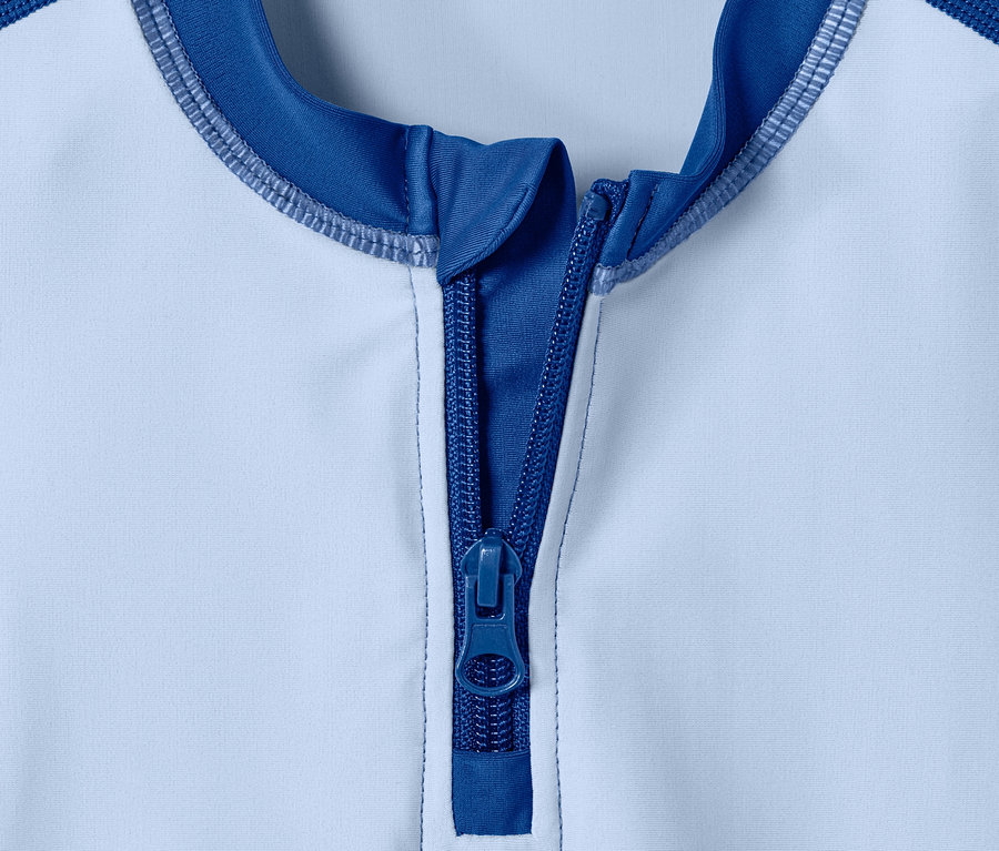 Detail modro-bílého UV ochranného oblečení se zipem.