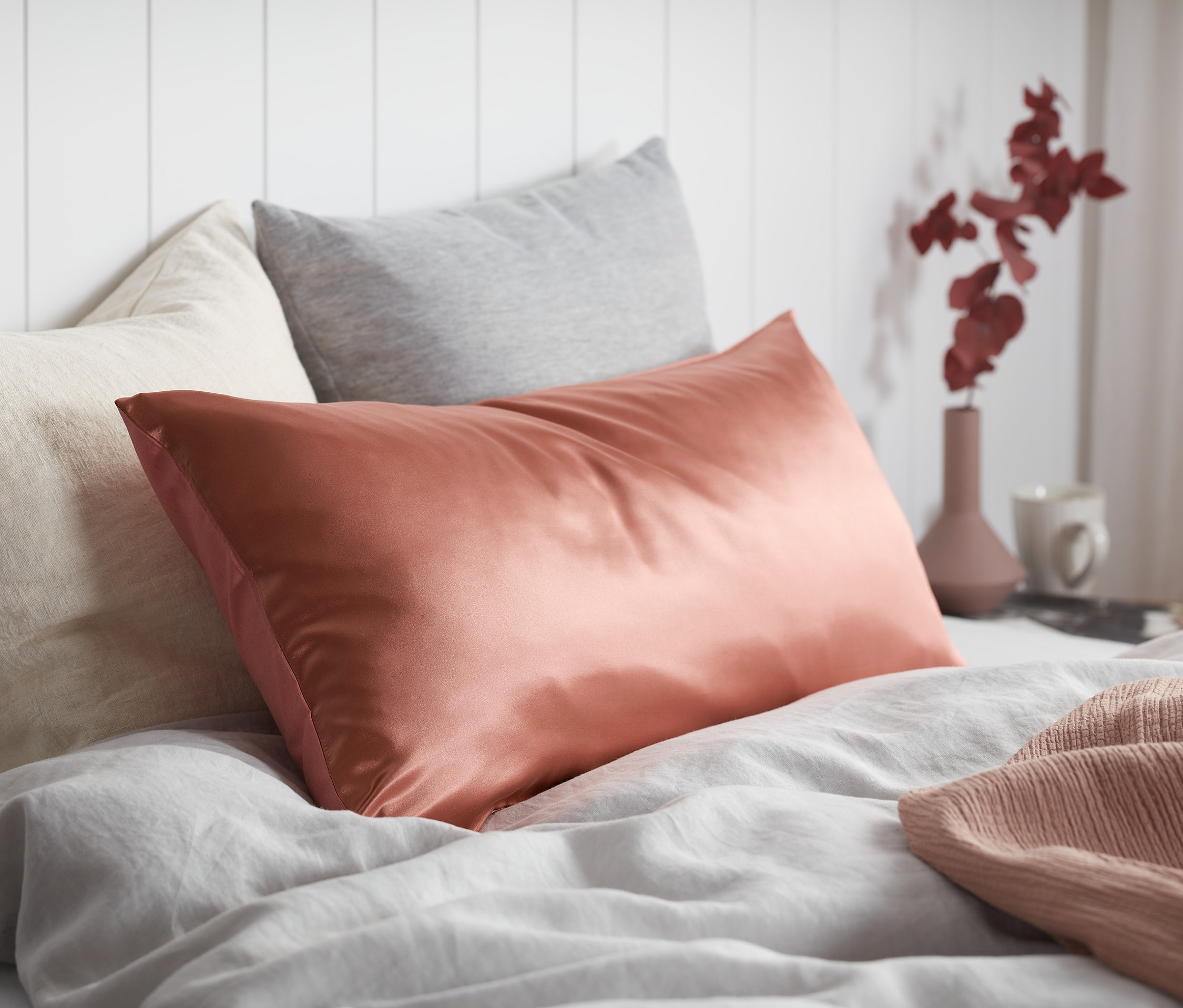 Na posteli leží hedvábný a bavlněný povlak na polštář.