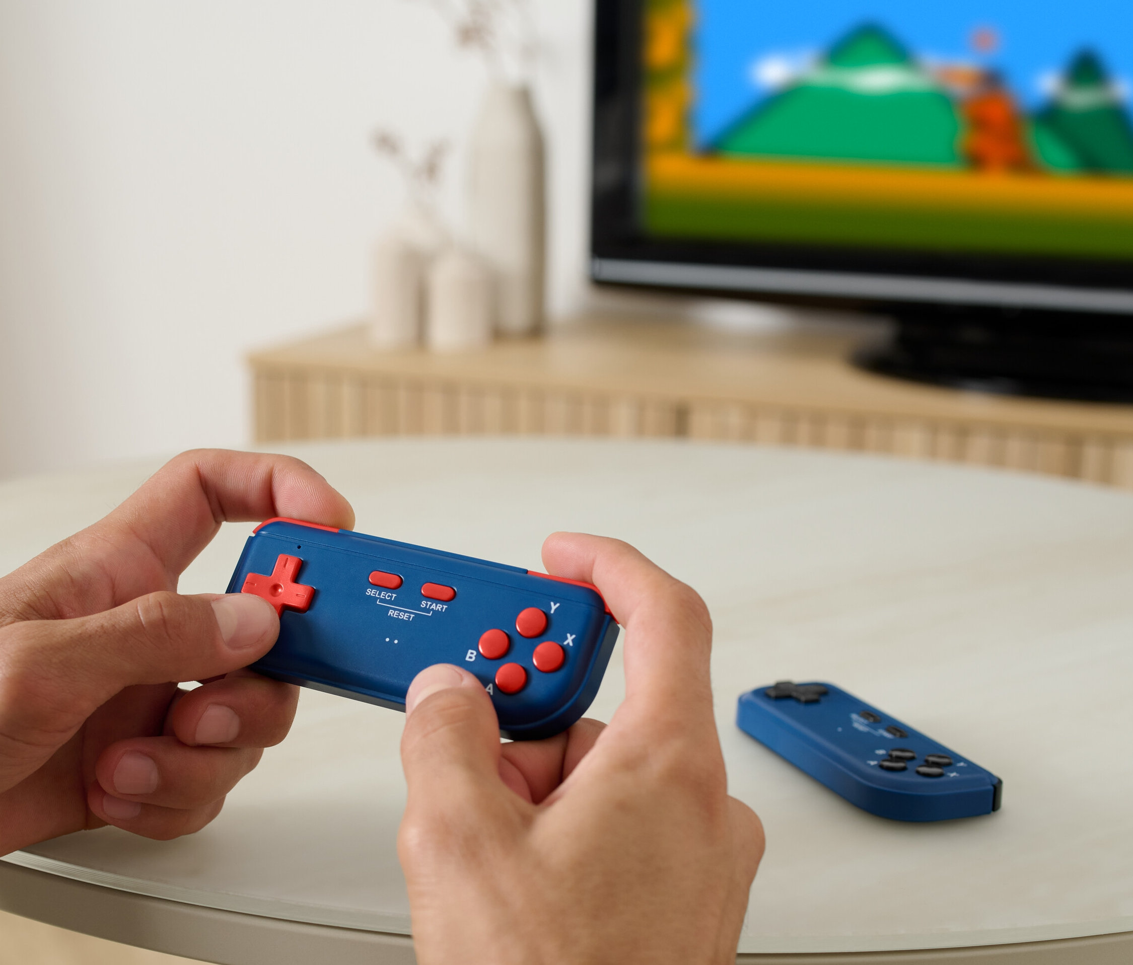 Muž hraje na retro herní konzoli k TV, v pozadí je vidět televize.