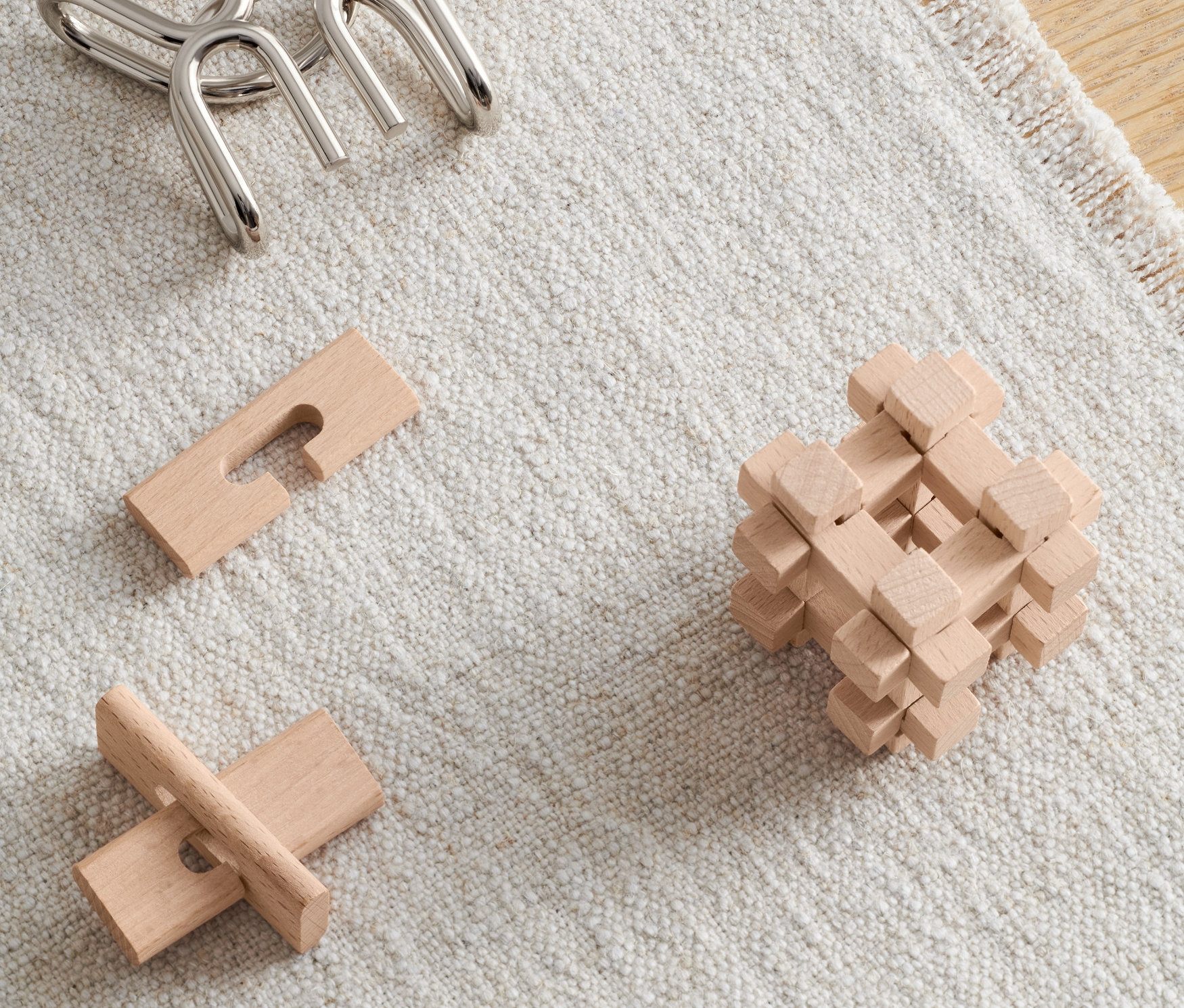 Na béžovém koberci leží tři hlavolamy.