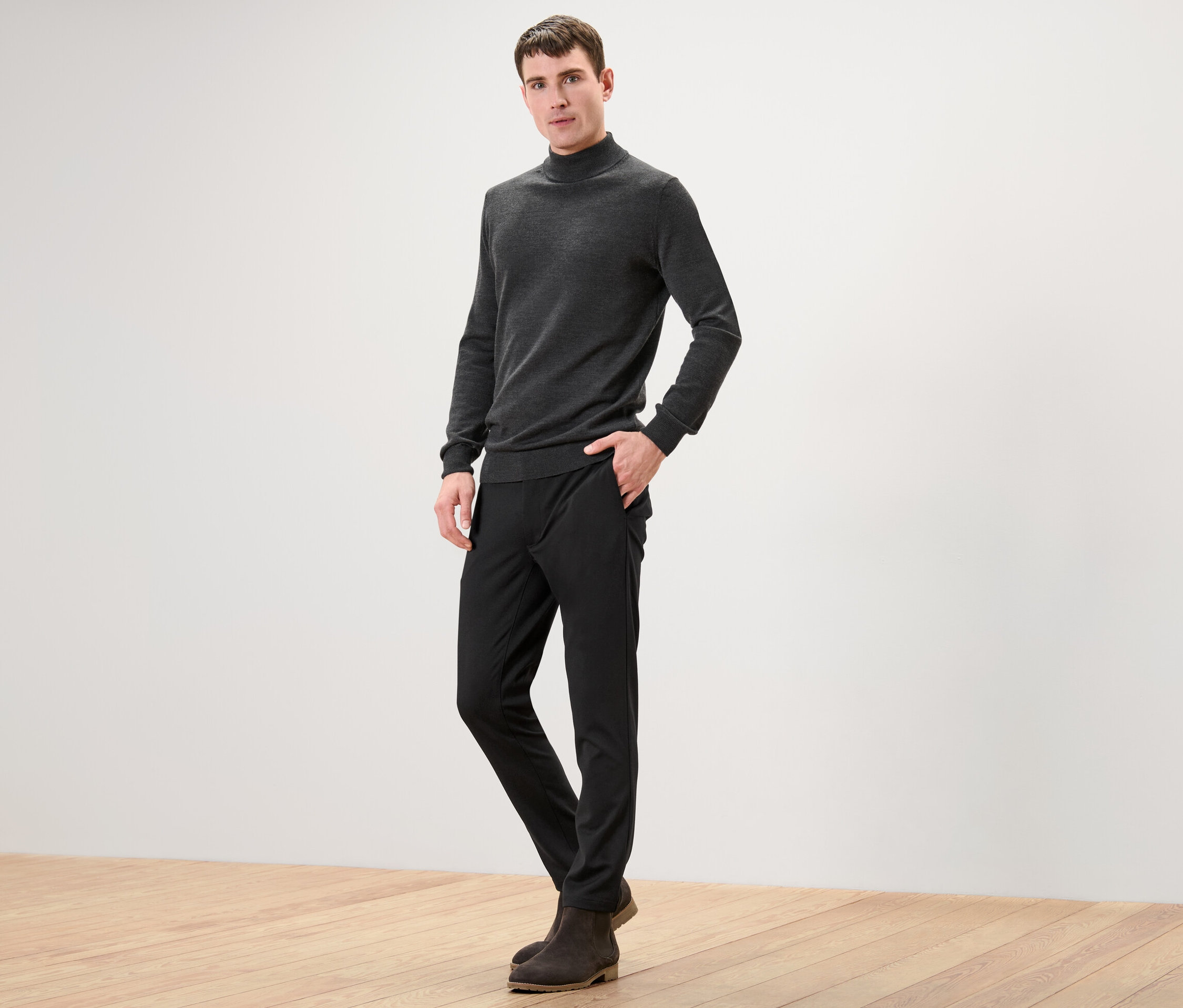 Muž stojí a pózuje na kameru v černých strečových kalhotách.