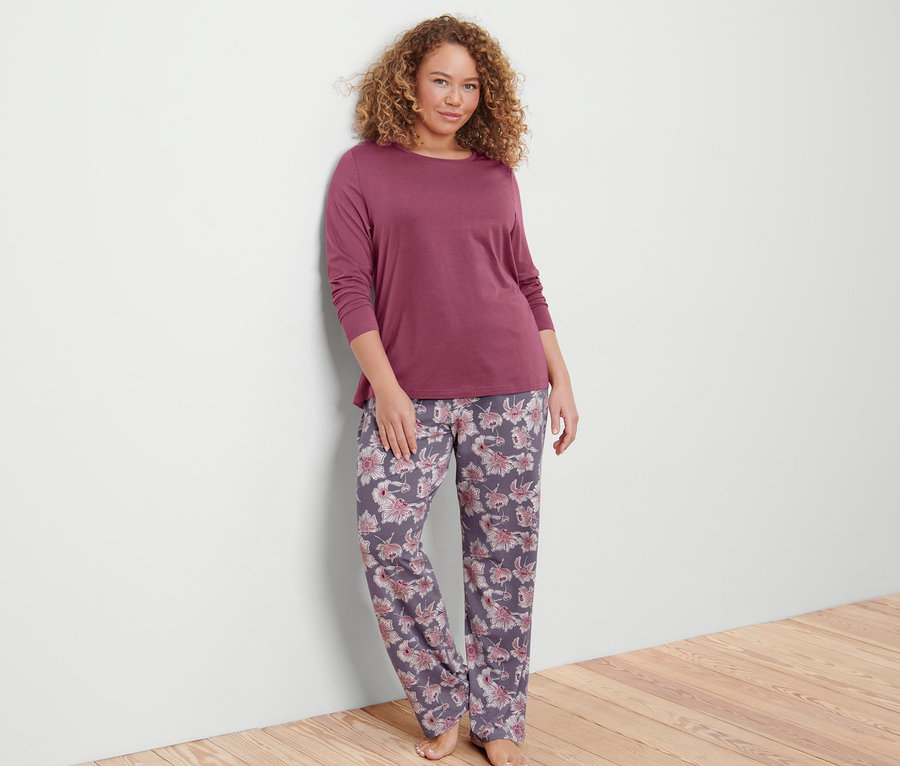 Žena opřená o stěnu má na sobě pyžamo.