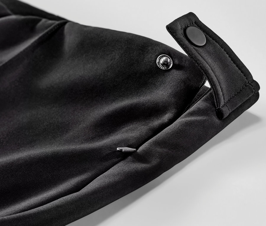 Detail softshellových lyžařských legín s kapsou na zip a zapínáním na patentky.