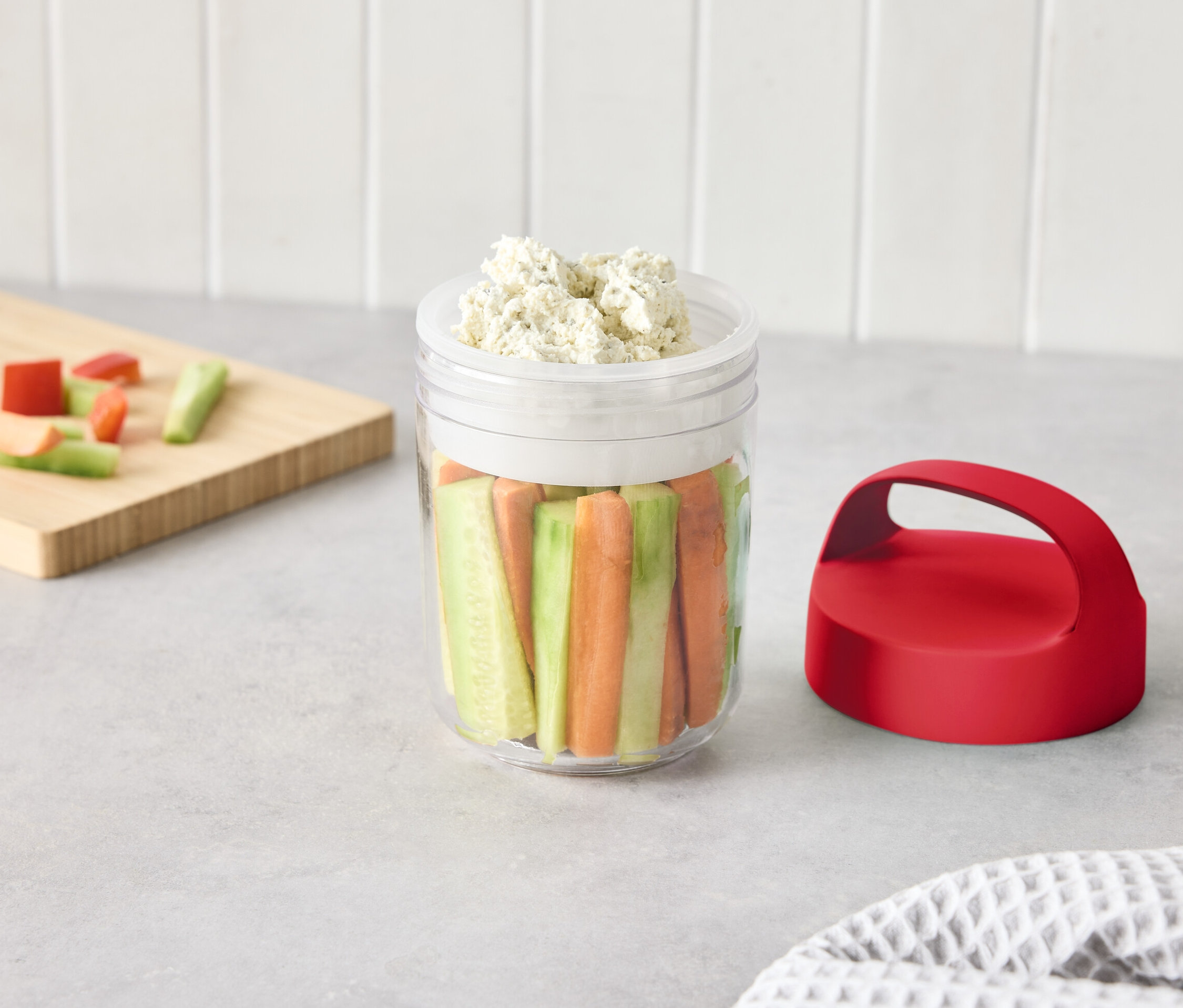 Sklenice s nakrájenou zeleninou a dipem na stole.