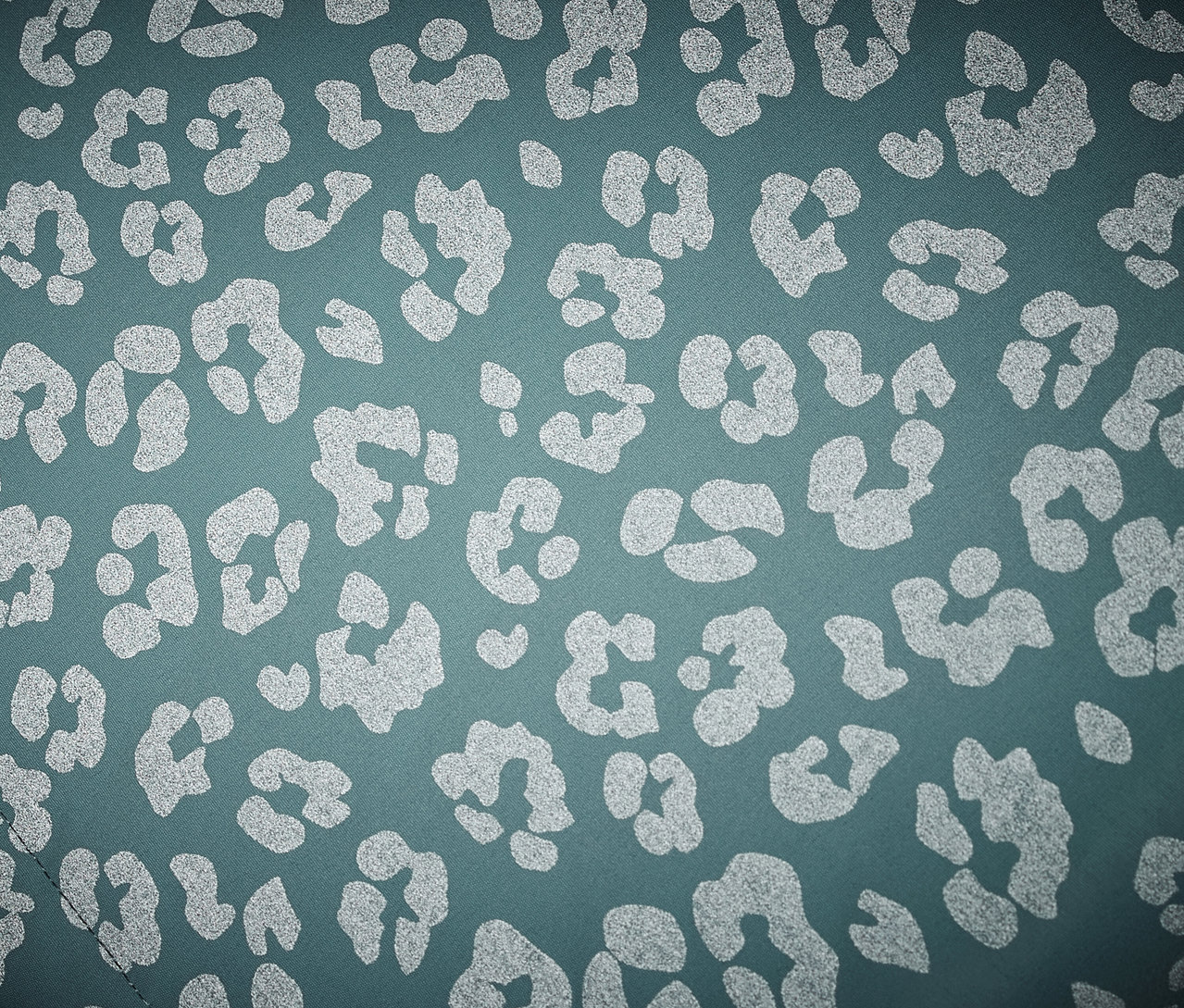 Detailní záběr na dětskou termo bundu do deště s reflexními prvky s leopardím vzorem.