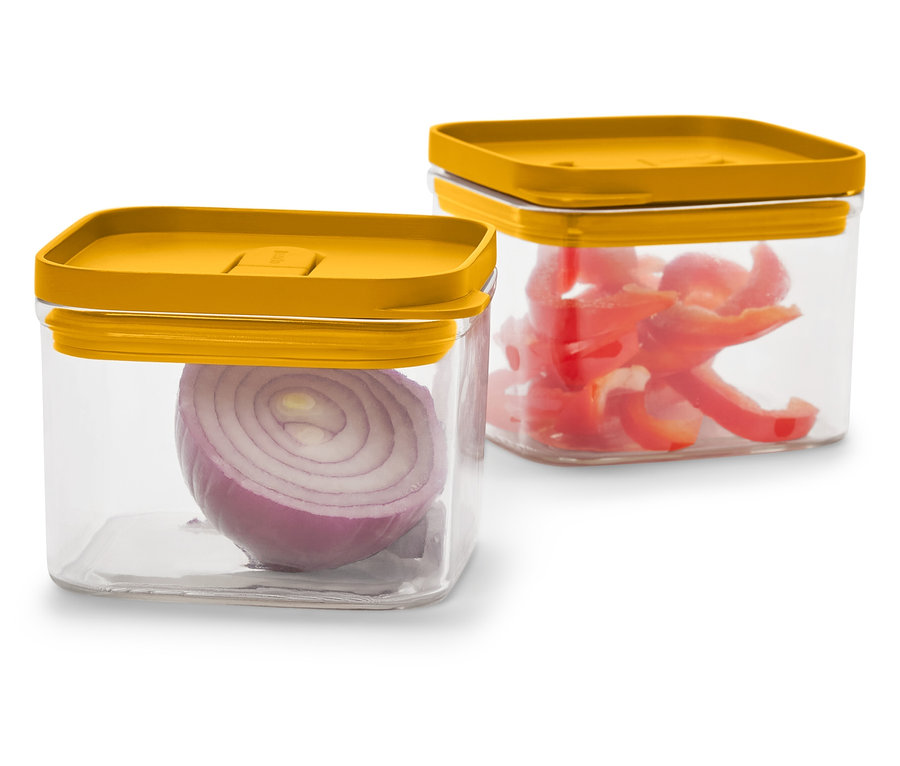 Dvě průhledné čtvercové nádoby s hořčicově žlutými víčky. Jedna s půlkou červené cibule, druhá s nakrájenou červenou paprikou.