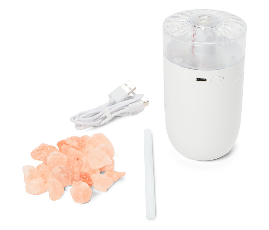 Bílý zvlhčovač vzduchu s USB kabelem, tyčinkou a hromadou růžových krystalů soli.