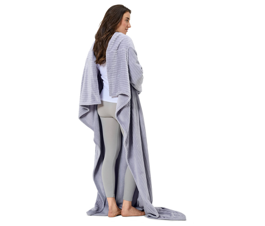 Žena stojící zády ke kameře, zabalená v šedé dece.