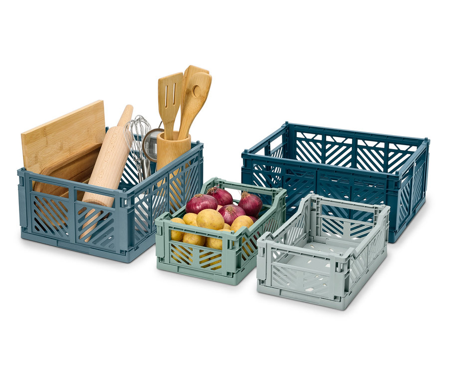 Čtyři skládací přepravky různých velikostí a barev, jedna s kuchyňským náčiním, jedna s bramborami.