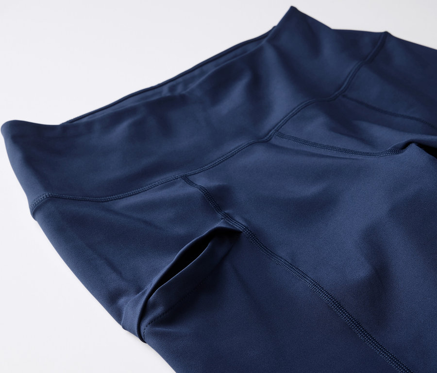 Detailní záběr na 3/4 trekingové legíny tmavě modré barvy s kapsou na boku.