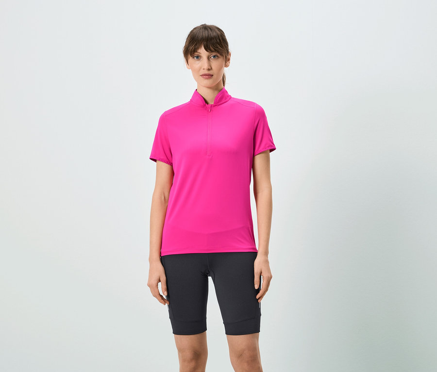 Žena má na sobě růžové tričko s krátkým zipem a černé šortky.