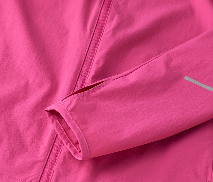 Detail růžové bundy se zipem a rukávem s otvorem pro palec.