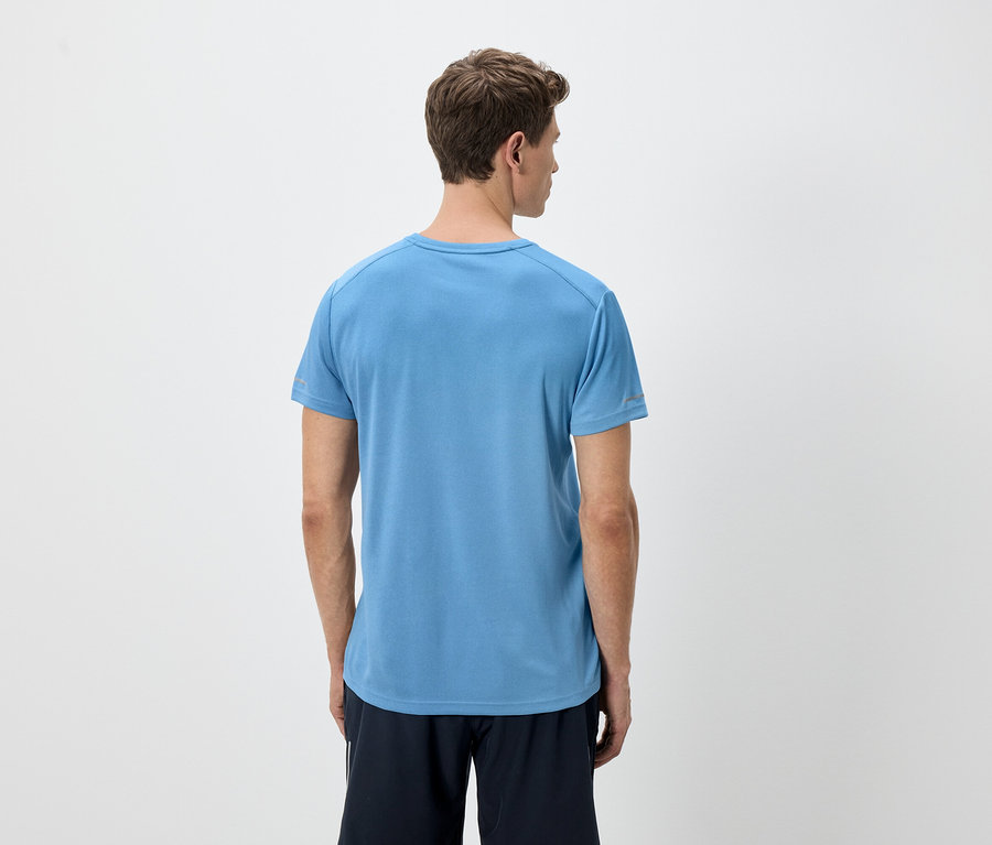 Pohled zezadu na muže se světle hnědými vlasy v modrém tričku a černých šortkách na bílém pozadí.