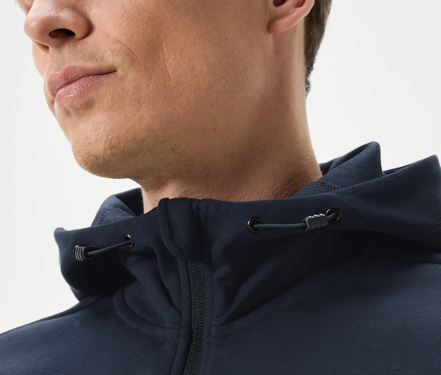 Detail muže v tmavě modré mikině s kapucí na zip.