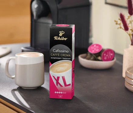 Na lince stojí kávovar vedle balení Caffè Crema Wake Up XL – 80 kapslí a šálku.