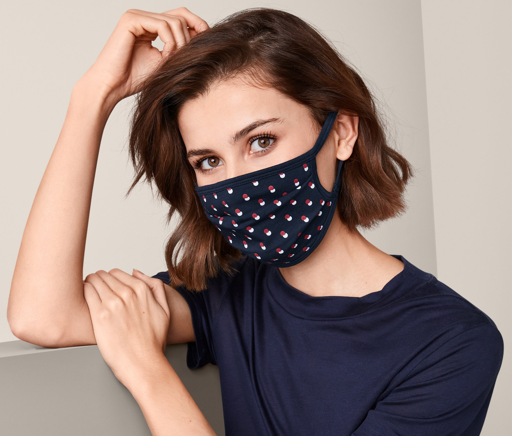 Žena nosí tmavě modrou ochrannou roušku, 3 ks, s červenými a bílými tečkami.