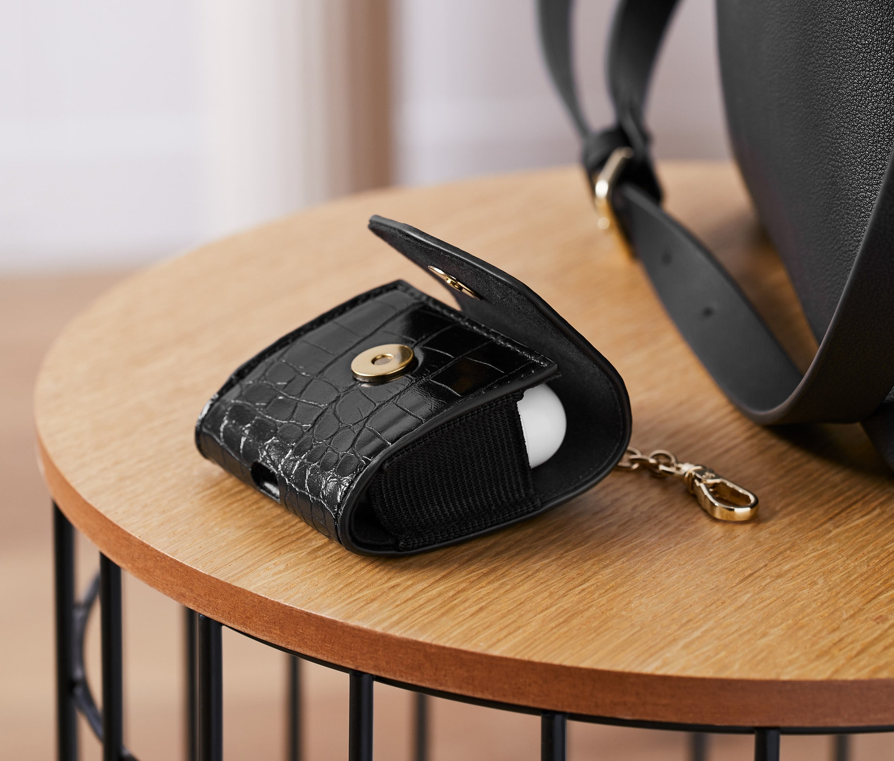 Černé pouzdro na sluchátka leží otevřené na stole.