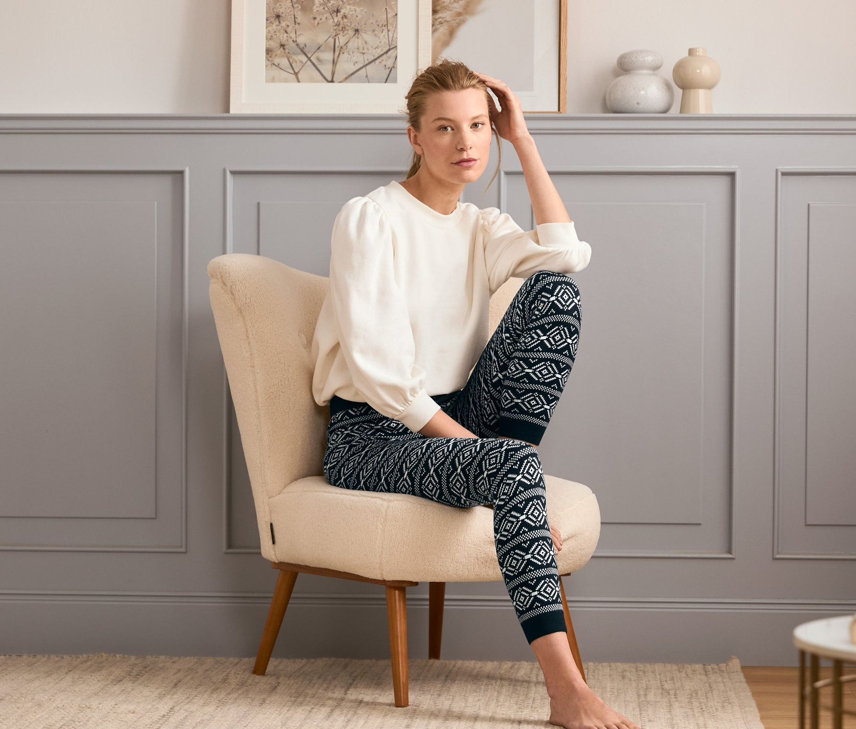 Žena sedí v křesle a má na sobě pletené legíny.