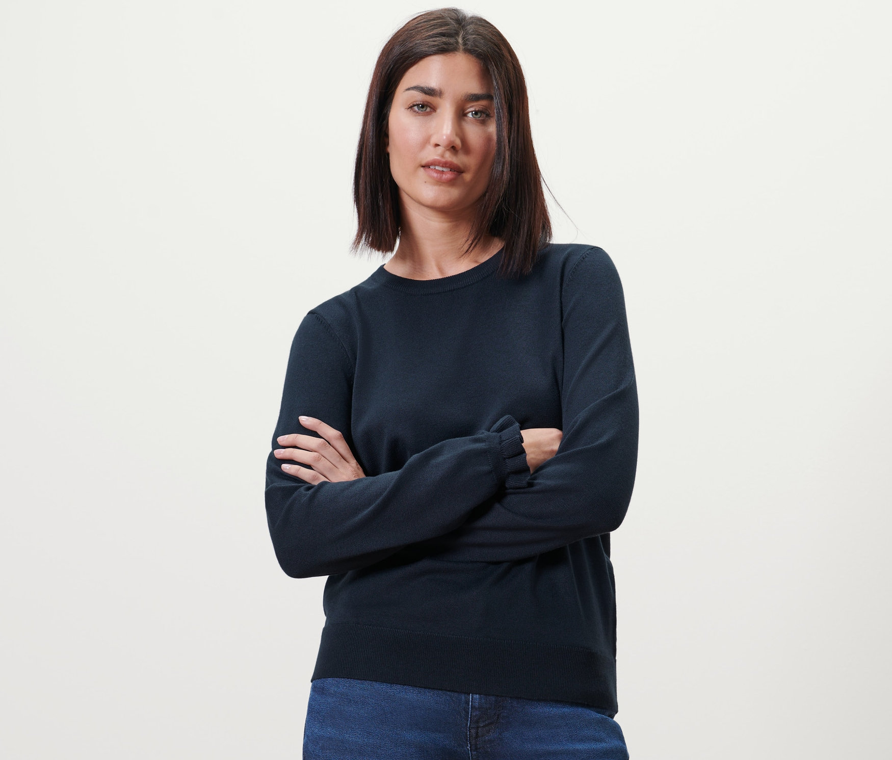 Žena se zkříženýma rukama pózuje ve svetru z jemné pleteniny s volánkovými detaily, tmavě modrý.