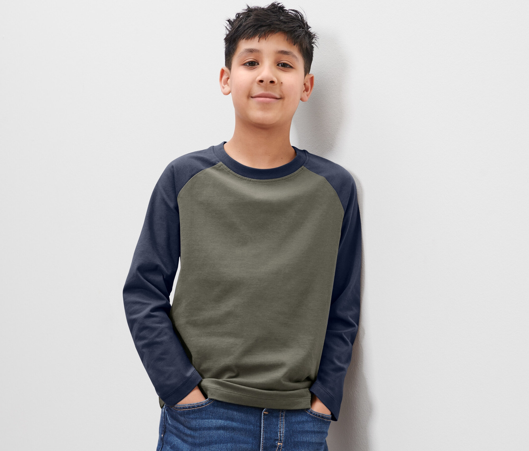 Chlapec pózuje v dětském tričku s dlouhým rukávem, 2 ks, opíraje se o bílou zeď.