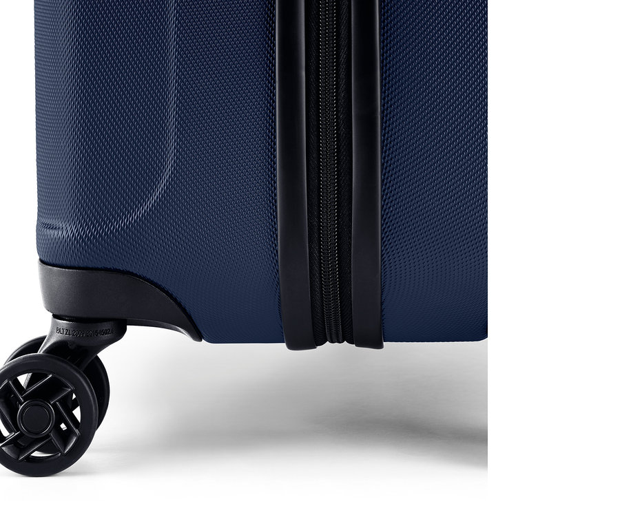 Detail modrého skořepinového kufru se zipem a kolečky.
