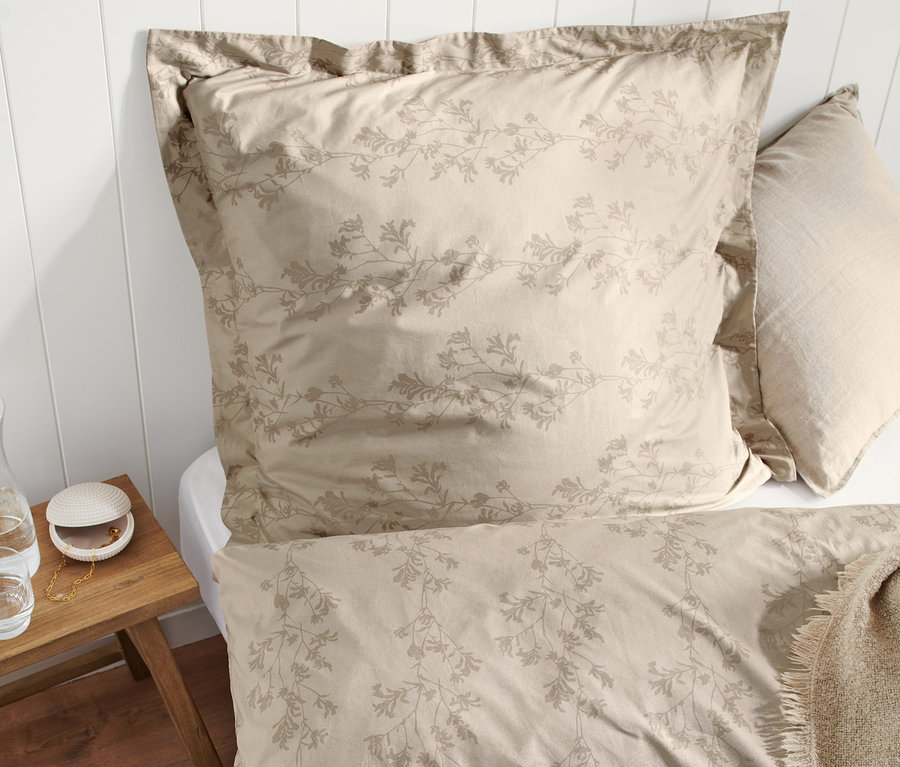 Béžové prémiové bavlněné povlečení s květinovým vzorem na posteli.