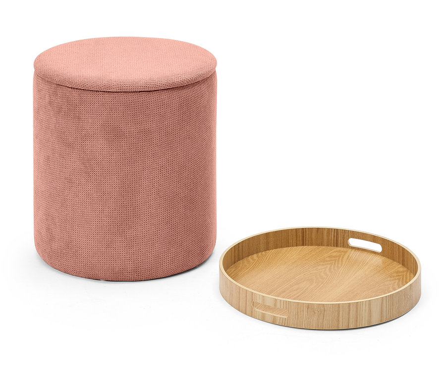 Růžový látkový taburet vedle kulatého dřevěného podnosu na bílém pozadí.