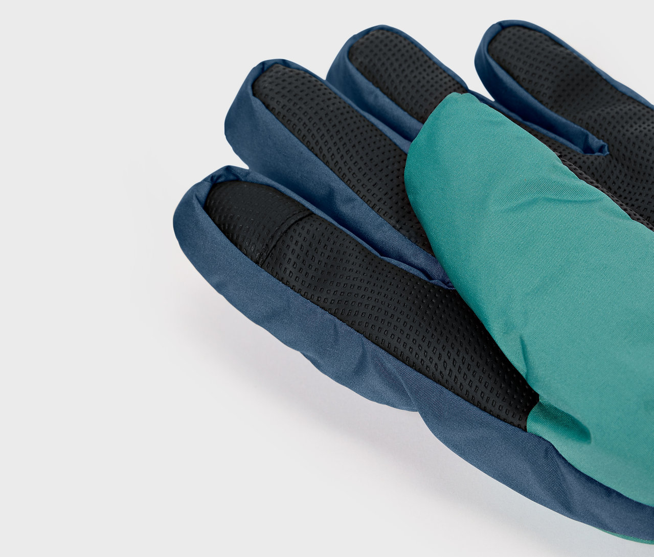 Detail modré rukavice s černou dlaní a zeleným prstem.