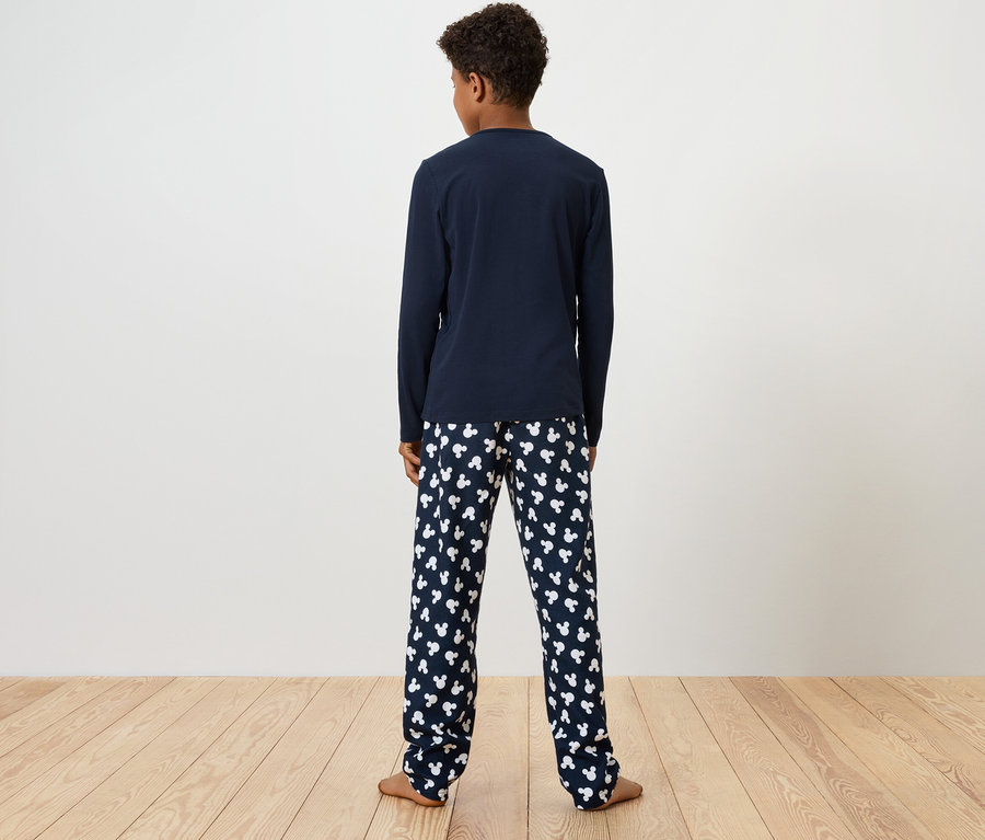 Chlapec stojí zády, má na sobě modré pyžamové tričko s dlouhým rukávem a pyžamové kalhoty s potiskem bílých medvídků.