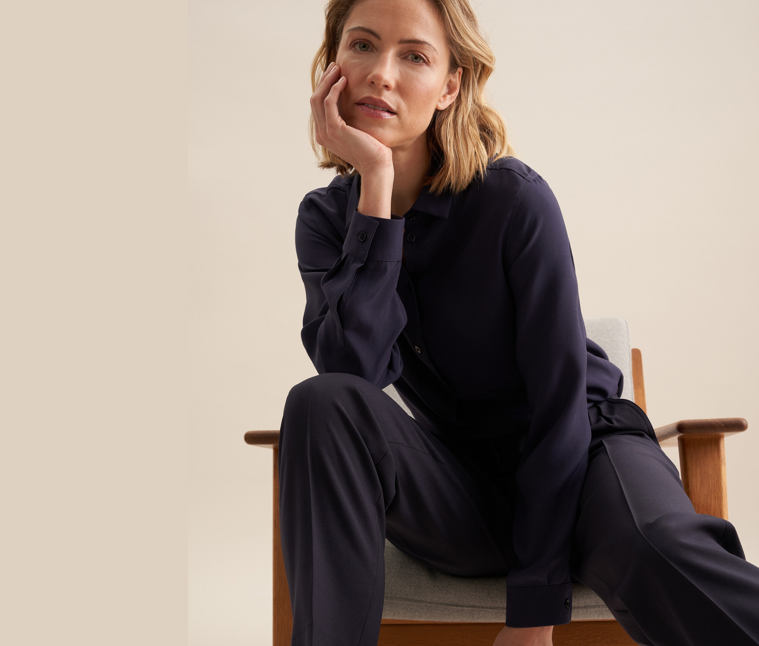 Žena sedí v křesle a má na sobě halenku Seidensticker z viskózy.