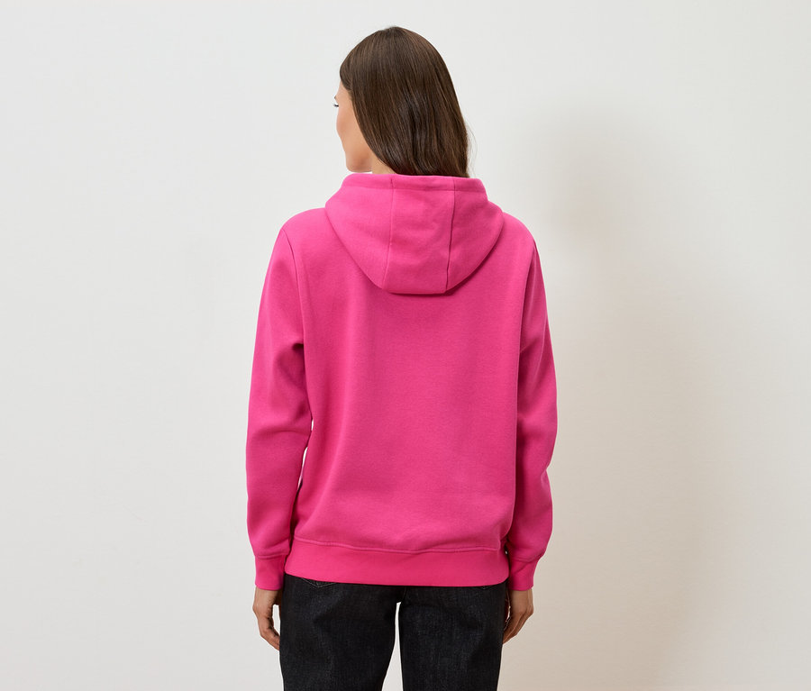 Zezadu pohled na ženu s hnědými vlasy v růžové mikině s kapucí a černých kalhotách.