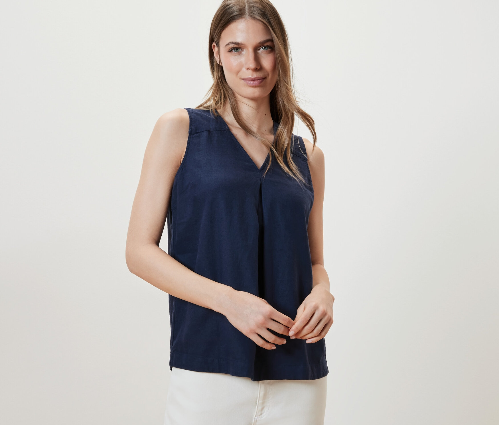 Žena pózuje v námořnicky modré lněné halence bez rukávů.